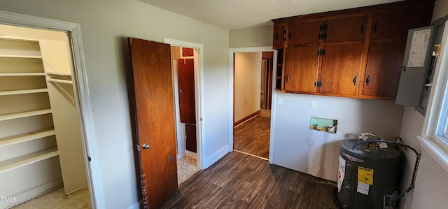 interior space featuring dark hardwood / wood-style flooring, cabinets, washer hookup, electric water heater, and a textured ceiling