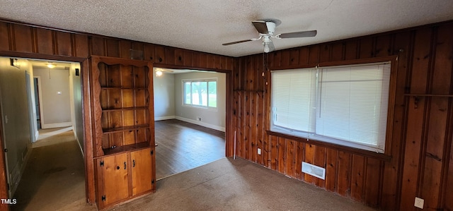 unfurnished room with ceiling fan, a textured ceiling, and wood walls