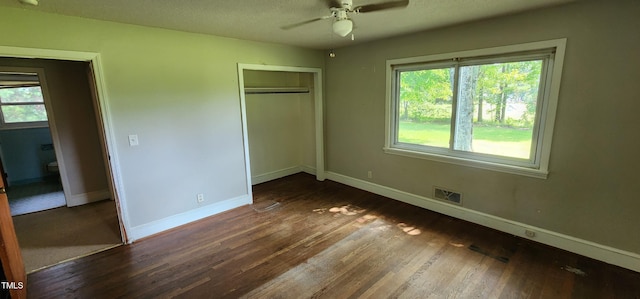 unfurnished bedroom with ceiling fan, dark hardwood / wood-style floors, a textured ceiling, and a closet