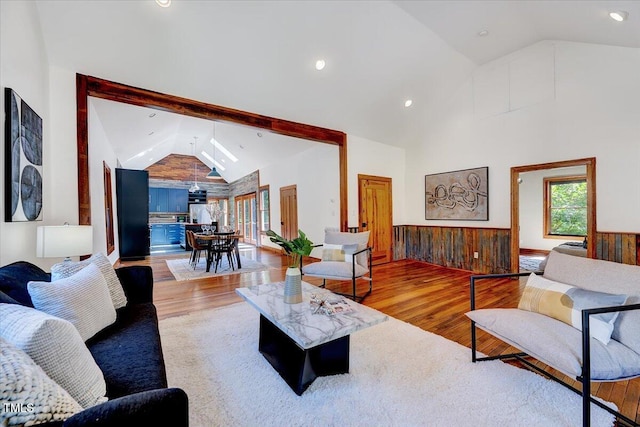 living room with high vaulted ceiling, wooden walls, and light hardwood / wood-style flooring