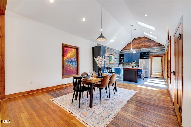 dining space featuring lofted ceiling with skylight and light wood-type flooring