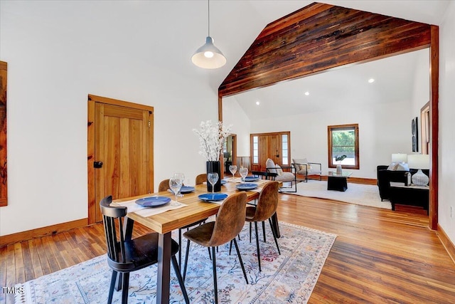 dining room with wood-type flooring and high vaulted ceiling