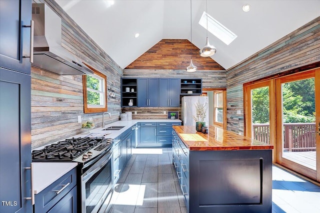 kitchen featuring sink, wooden counters, appliances with stainless steel finishes, a kitchen island, and decorative light fixtures