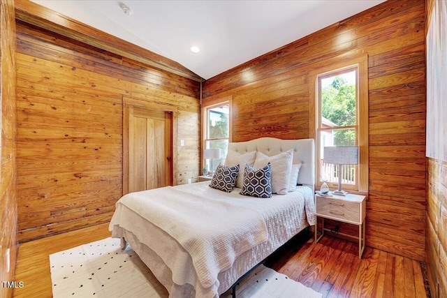 bedroom featuring wood-type flooring, lofted ceiling, and wooden walls