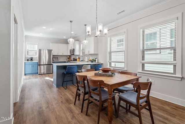 dining area featuring ornamental molding, a chandelier, and hardwood / wood-style floors