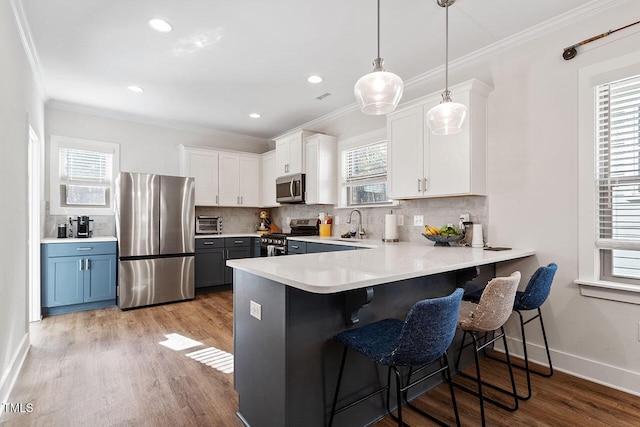 kitchen with hanging light fixtures, a breakfast bar area, stainless steel appliances, and white cabinets