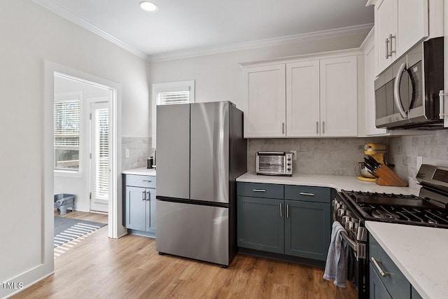 kitchen with crown molding, appliances with stainless steel finishes, light hardwood / wood-style floors, and white cabinets