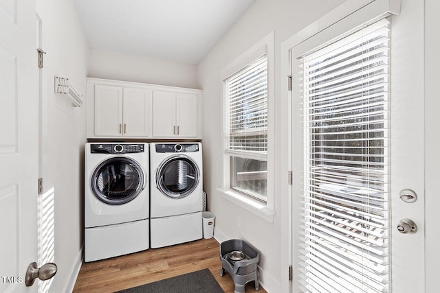 laundry room with cabinets, washer and clothes dryer, and light wood-type flooring