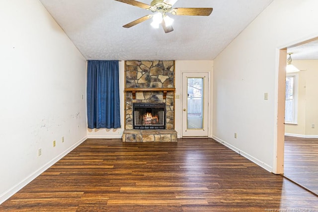 unfurnished living room with ceiling fan, a textured ceiling, dark hardwood / wood-style flooring, a stone fireplace, and vaulted ceiling