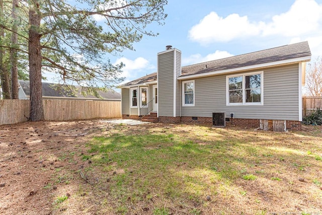 rear view of property featuring a lawn, entry steps, a chimney, and fence