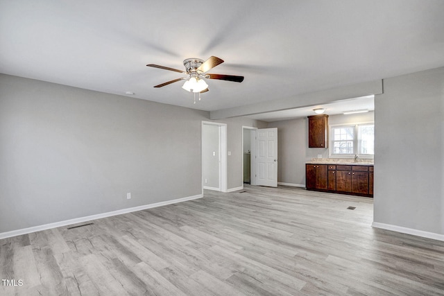 unfurnished living room featuring sink, light hardwood / wood-style flooring, and ceiling fan