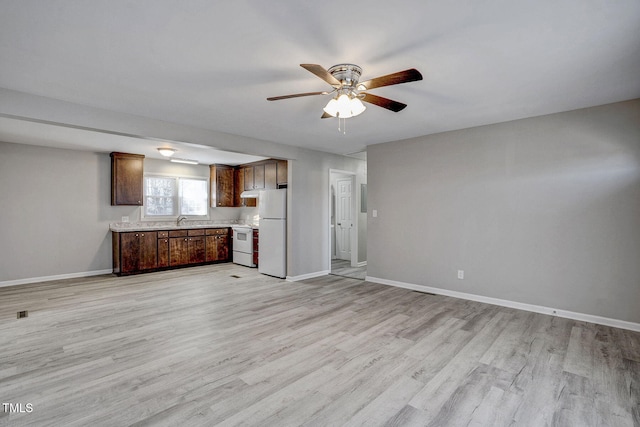 unfurnished living room with ceiling fan, sink, and light hardwood / wood-style flooring