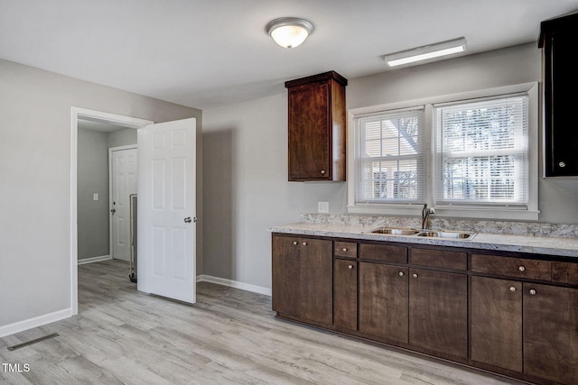 kitchen featuring sink, dark brown cabinets, and light hardwood / wood-style flooring