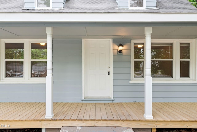 property entrance with covered porch and roof with shingles