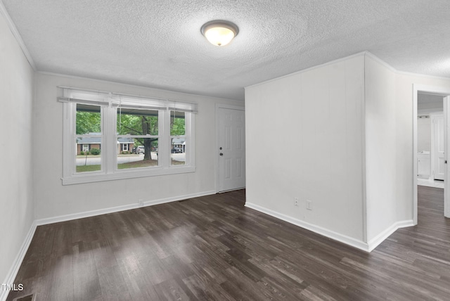 empty room with a textured ceiling, dark wood-type flooring, baseboards, and ornamental molding