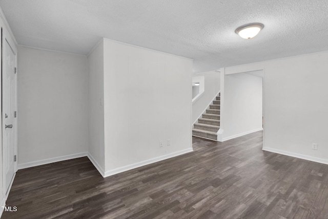 empty room featuring dark wood-type flooring, a textured ceiling, stairway, and baseboards