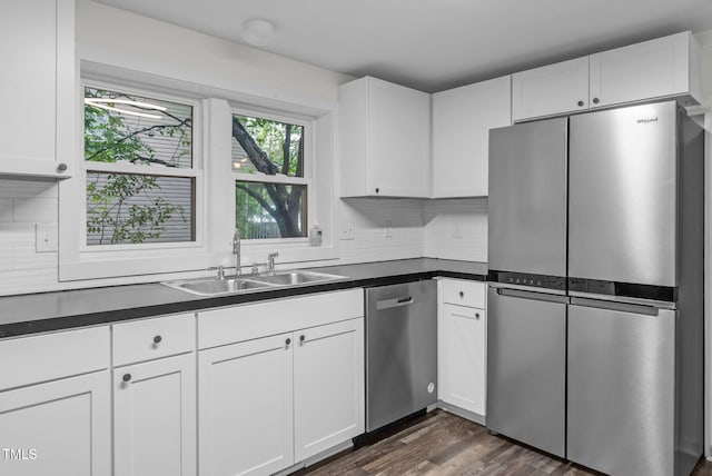 kitchen featuring appliances with stainless steel finishes, a sink, dark countertops, and white cabinets