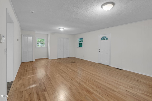 spare room with a textured ceiling, light wood-style floors, and baseboards