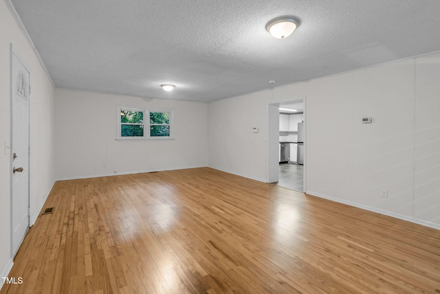 empty room with light wood-style flooring, a textured ceiling, and baseboards