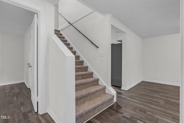 stairs with wood finished floors, a textured ceiling, and baseboards
