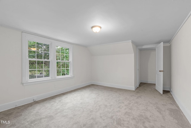 additional living space with light colored carpet, baseboards, and lofted ceiling
