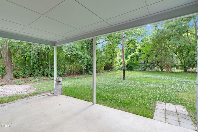 view of green lawn with a patio and view of scattered trees