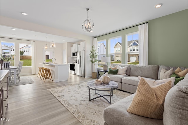 living room featuring sink, light hardwood / wood-style flooring, and a notable chandelier