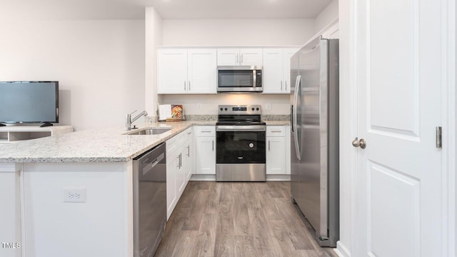 kitchen featuring stainless steel appliances, light stone countertops, sink, and white cabinets