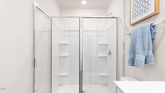 bathroom featuring vanity, toilet, and a shower with door