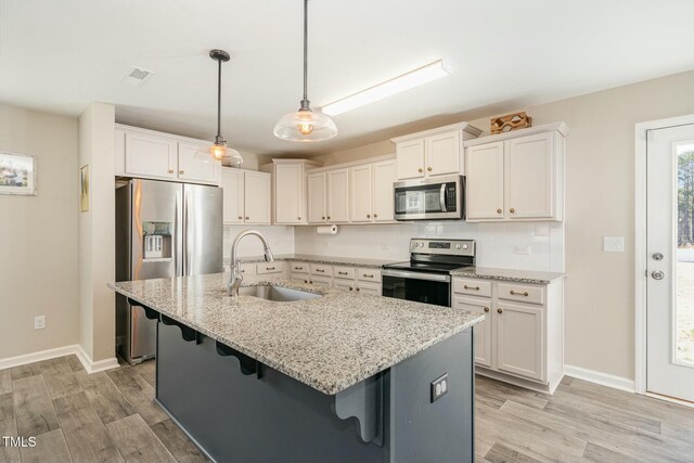 kitchen with appliances with stainless steel finishes, light stone countertops, sink, and white cabinets