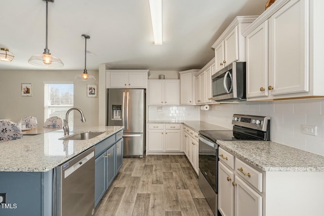 kitchen featuring pendant lighting, sink, white cabinets, stainless steel appliances, and blue cabinetry