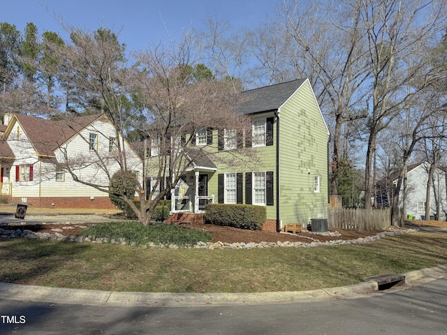 colonial inspired home with central AC unit and a front lawn