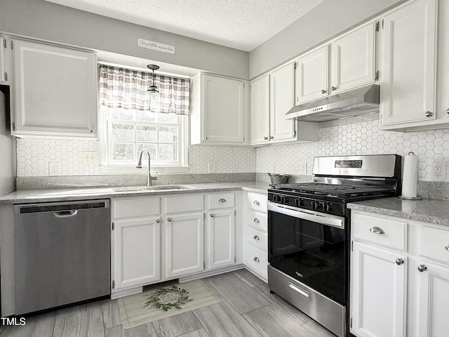 kitchen with appliances with stainless steel finishes, tasteful backsplash, sink, white cabinets, and a textured ceiling