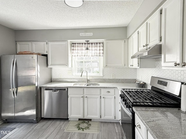 kitchen with sink, white cabinets, decorative backsplash, stainless steel appliances, and a textured ceiling