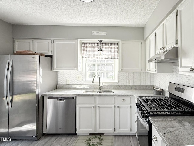 kitchen featuring sink, white cabinetry, a textured ceiling, stainless steel appliances, and backsplash