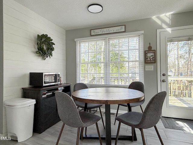 dining space with a healthy amount of sunlight, light hardwood / wood-style floors, and a textured ceiling