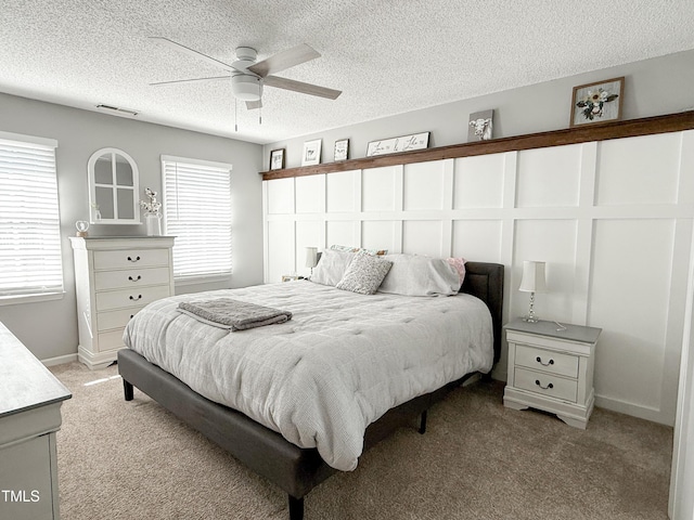 carpeted bedroom featuring multiple windows, ceiling fan, and a textured ceiling