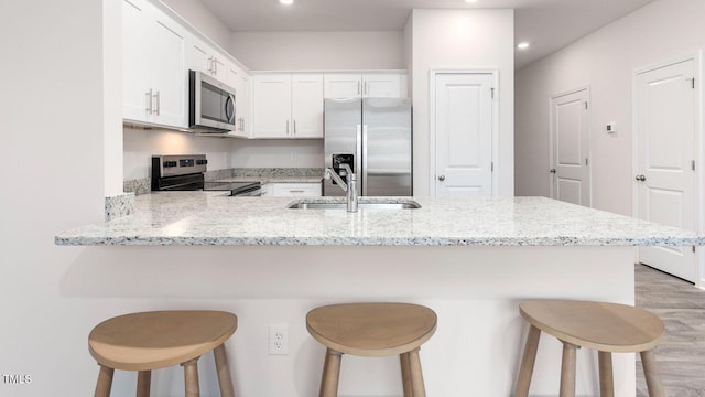 165 Holton St, Smithfield, NC 27577 - kitchen featuring a breakfast bar, white cabinets, a peninsula, and appliances with stainless steel finishes