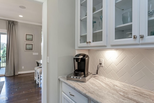 bar featuring crown molding, tasteful backsplash, light stone countertops, white cabinets, and dark hardwood / wood-style flooring