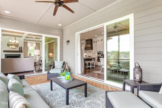 living room with hardwood / wood-style floors, ceiling fan, and wood walls