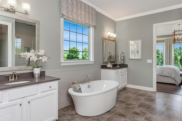 bathroom with ornamental molding, a healthy amount of sunlight, a bathtub, and vanity