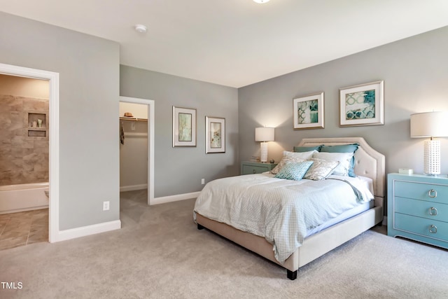 bedroom with ensuite bathroom, a spacious closet, light carpet, and a closet