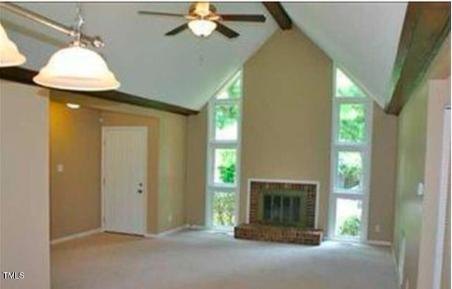 unfurnished living room featuring beamed ceiling, a brick fireplace, a healthy amount of sunlight, and light colored carpet