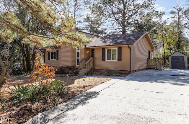 view of front of home with an outbuilding, roof with shingles, a storage unit, crawl space, and driveway