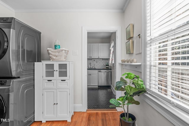 laundry room featuring sink, crown molding, light hardwood / wood-style flooring, and stacked washer / dryer