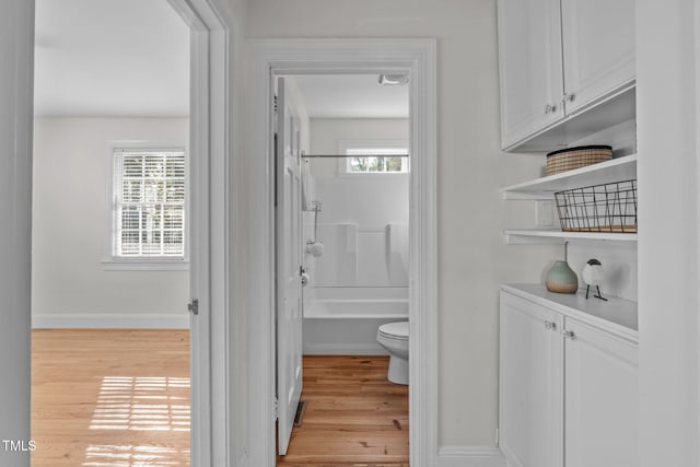 bathroom with shower / bathing tub combination, hardwood / wood-style floors, and toilet