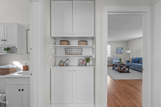 bar with white cabinets and light wood-type flooring