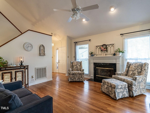 living room with a premium fireplace, lofted ceiling, hardwood / wood-style floors, and ceiling fan