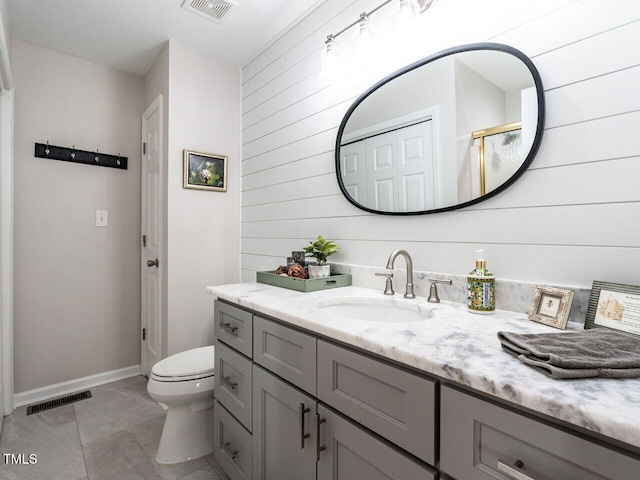 bathroom with vanity, a shower with shower door, wood walls, and toilet