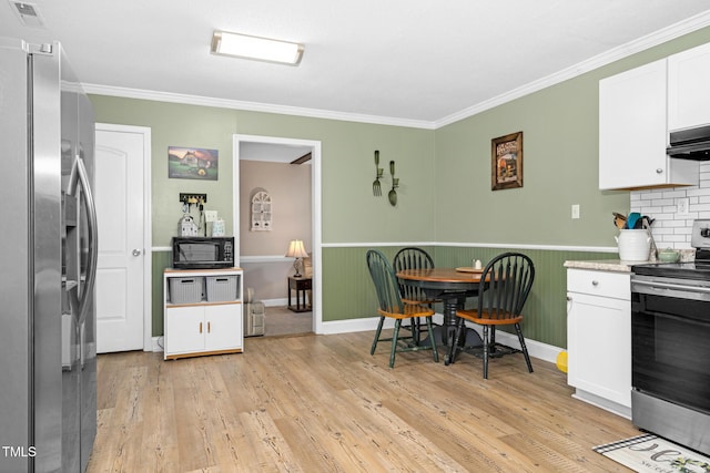 kitchen featuring visible vents, white cabinets, wainscoting, light wood-style flooring, and appliances with stainless steel finishes